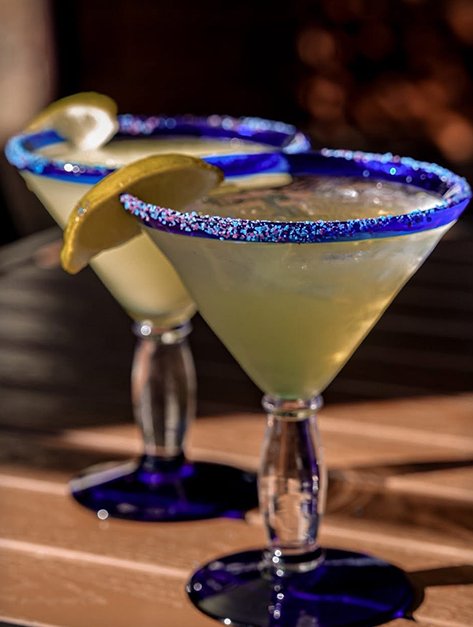 A lime margarita with a blue sugared rim